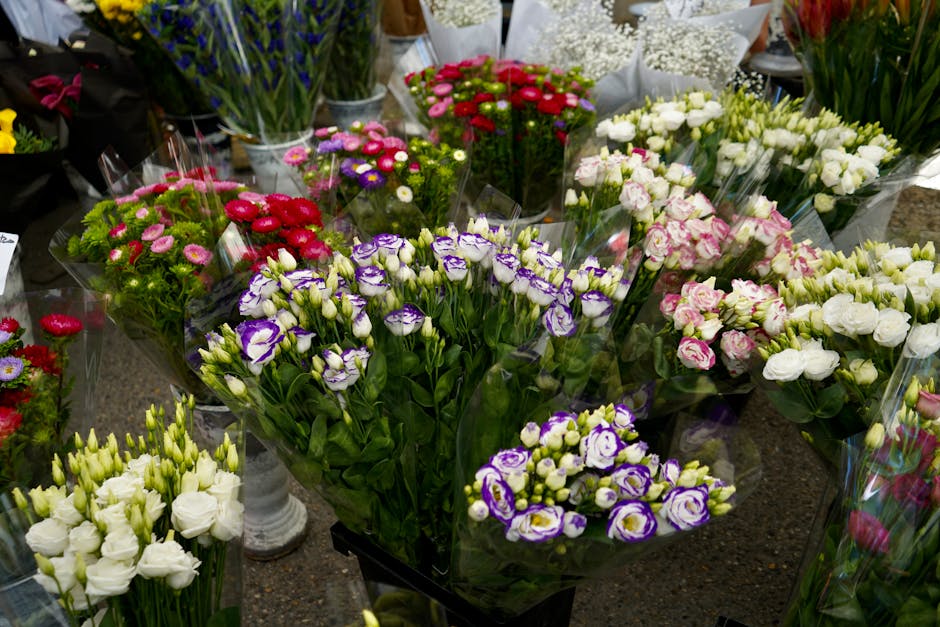 A diverse selection of fresh floral arrangements displayed on a countertop at flowerswillesden.co.uk, featuring bouquets of sweet William with purple and white blooms, pink and red roses, white lisian