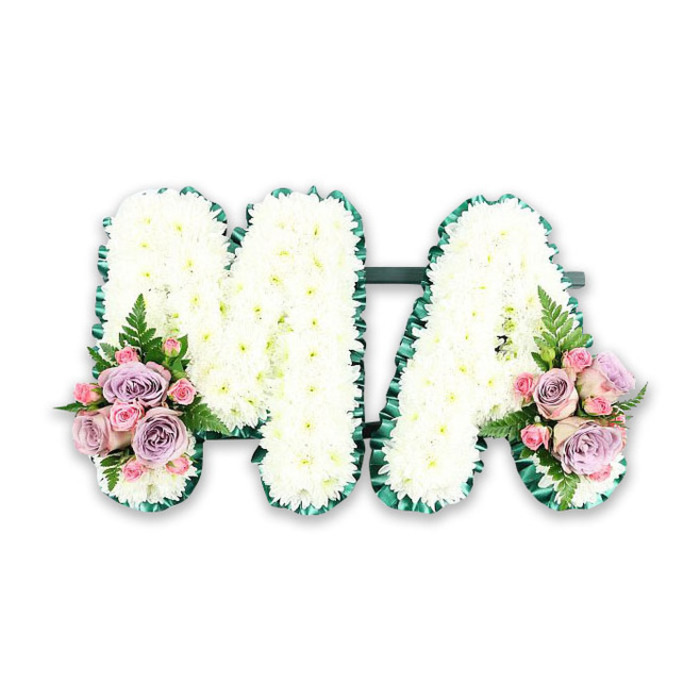 This image shows a refined floral tribute spelling MA in tall, bold capital letters, designed as a personalised farewell for a mother or someone known by these initials. The letters are constructed on a discreet frame and densely packed with snow-white chrysanthemums, the blossom heads circular and slightly domed, overlapping like a field of tiny cushions. Their texture appears soft and inviting, suggesting the comforting touch of a hand on a familiar shoulder. A deep emerald-green pleated ribbon neatly edges both the M and the A, following every line and angle, giving the design a polished, almost tailored look that stands out clearly against the white floral surface. The overall finish is clean and meticulous, reminiscent of the careful attention to detail you might see in bespoke funeral flowers prepared for families along Willesden High Road or near Roundwood Park. At the lower left foot of the M and the lower right foot of the A, two complementary floral clusters soften the structure with colour and movement. Each cluster features a blend of pastel pink roses, lilac or soft lavender roses, and petite pink spray roses, some in full bloom and others in tighter bud, symbolising different stages of life and memory. Threads of delicate green fern and foliage extend gently from the roses, adding height, texture, and a touch of natural wildness to an otherwise very structured piece. Set against a plain white background, every detail of the tribute is clear: the symmetry of the letters, the precision of the chrysanthemum placement, and the tender hues of the accent flowers. The arrangement feels deeply respectful and personal, ideal for a funeral or memorial service in Willesden, offering a quiet yet unmistakable declaration of love and remembrance.