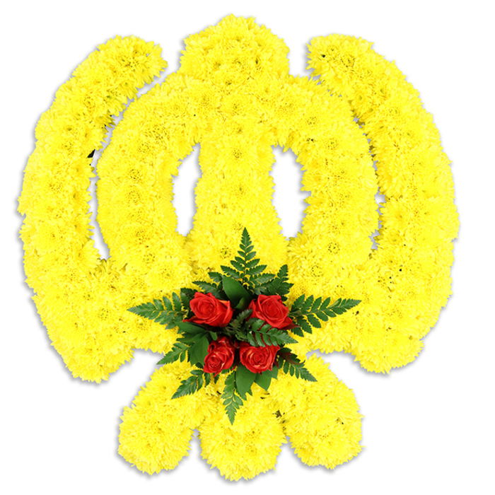 An exquisitely detailed floral Khanda commands attention against a stark white backdrop: the traditional Sikh symbol - a central double-edged sword, the circular chakram, and two crossed kirpans - is meticulously formed from thousands of small, sun-bright yellow chrysanthemum blooms. The dense, deliberate packing of each blossom produces a tactile, almost plush surface that lends gentle relief to the emblem's sweeping curves and defined edges. At the geometric centre, where several elements meet, a deliberate punctuation of five to six deep red roses is arranged into a compact cluster and cushioned by dark green fern fronds; the glossy, finely divided leaves lift the roses visually and texturally, heightening their rich colour and the arrangement's solemn focal point. The white studio background and the soft grey shadow below emphasize the tribute's form and suggest a physical, freestanding memorial wreath suitable for services at local halls or gurdwaras in the Willesden and Dollis Hill area. There is an understated scent profile - the dry, green notes of chrysanthemum mingling with the mature, slightly sweet perfume of garden roses - that quietly anchors a room without overwhelming it. As crafted by florists familiar with community needs around Neasden and Gladstone Park, the piece is both a work of religious respect and floral artistry: restrained, vibrant, and composed to convey honour, remembrance, and solidarity in times of solemn reflection.