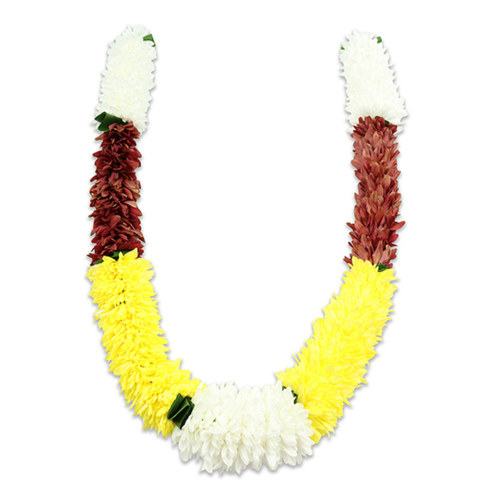 Set against a bright white background that emphasises its saturated colours, this U-shaped floral garland is a study in texture and cultural intent. Each arm begins with a dense ring of small, fluffy white blooms-crafted from fabric to resemble jasmine or tiny chrysanthemums-that create an airy, auspicious top. Beneath these, a concentrated swath of maroon or reddish-brown petals forms a grounding midsection, its depth of tone giving the garland a dignified warmth. The yellow sections that follow are generous and plush, worked into long, voluminous curves that define the U's lower sweep; their bright cheer contrasts beautifully with the darker maroon above. Where the arms meet at the bottom, a central, wider cluster of white chrysanthemum-like fabric flowers becomes the composition's heart, accentuated by small dark green leaf motifs that mark colour transitions and lend a touch of visual punctuation. The piece reads as handcrafted: thousands of little cloth petals overlap and ripple, stitched into place to mimic natural bloom density while offering longevity for repeated ceremonial use. Viewed in the soft studio light, the garland throws a subtle shadow that helps reveal the sculpted form and the tactile, almost textile-like quality of the construction. Commonly used for Hindu puja, temple offerings, weddings and seasonal festivals such as Diwali or Holi, this style of mala carries layers of meaning-white for purity, yellow for prosperity, maroon for devotion-and would be equally at home adorning an altar in a Willesden home near Willesden Junction or decorating a ceremonial doorway in nearby Neasden. The overall effect is respectful, celebratory and crafted with patient skill.
