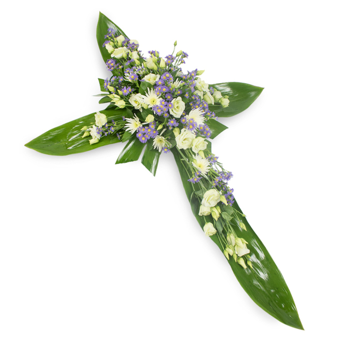 Set against a plain white background and captured from a slightly raised viewpoint, this dignified cross is crafted from glossy, tropical-style green leaves arranged to define each arm and the central core of the Christian symbol. The leaves' smooth, waxy surfaces and visible veins form a lush, protective platform for the floral embellishments that gather at the centre and run along the main axis. There, clusters of creamy ivory and pure white lisianthus-soft, ruffled and layered-are paired with small, rounded white chrysanthemum or spray buds that add compact texture and quiet luminosity. Intermingled with these are abundant sprays of pale lavender limonium or tiny aster-like flowers, their starry faces introducing a gentle cool tone and a sense of depth that prevents the design from feeling flat. Wisps of fine green filler foliage are tucked throughout to create softness along the edges and a natural transition between leaf and bloom. The piece is evenly lit so the tactile contrasts-the sleek leaves and the feathery petals-are clear and invitational, as though a calm breeze had just passed across a morning garden. As a memorial or sympathy tribute, this cross communicates dignity, solace and faith; it is the kind of arrangement local families in Willesden might request for funerals or church services along Willesden High Road and nearby neighbourhoods seeking a composed and reverent floral message.